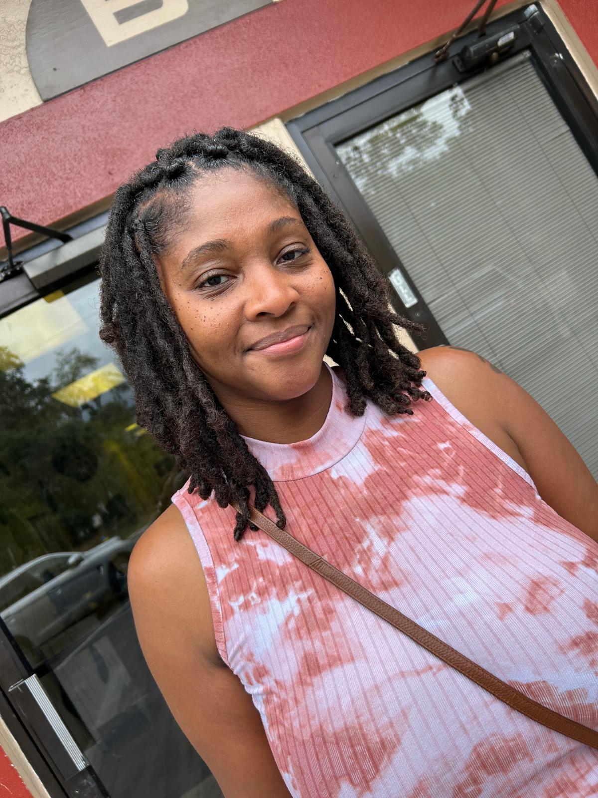 Joyful client with beautiful shoulder-length crown locs radiating confidence