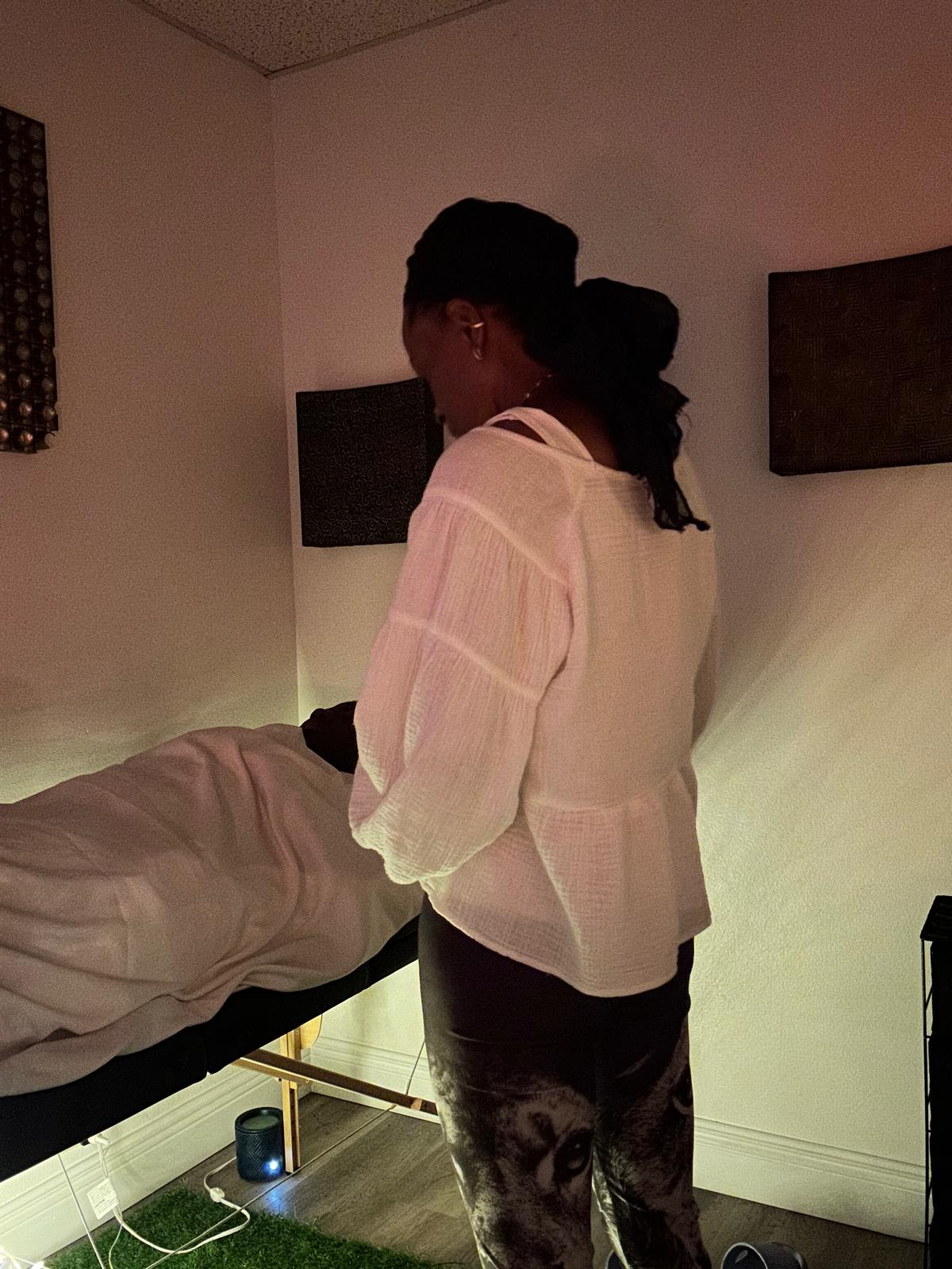 Practitioner in flowing white attire working in sacred treatment space with Four Elements art